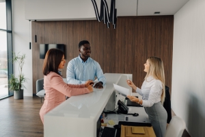 Female Apartment Concierge Assisting Guests Checking in at Her Desk